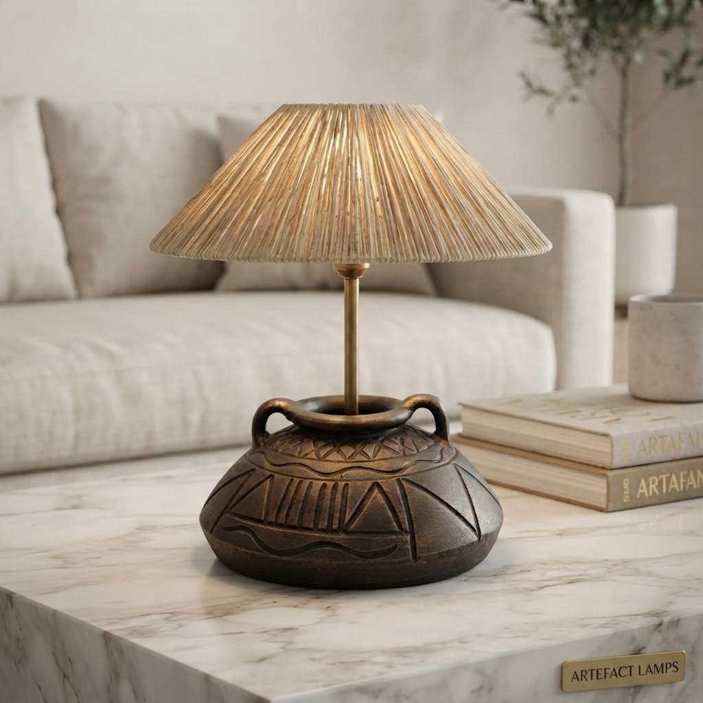 A decorative table lamp with a textured beige fringed shade and an antique bronze carved ceramic base, styled on a marble table in a living room setting.